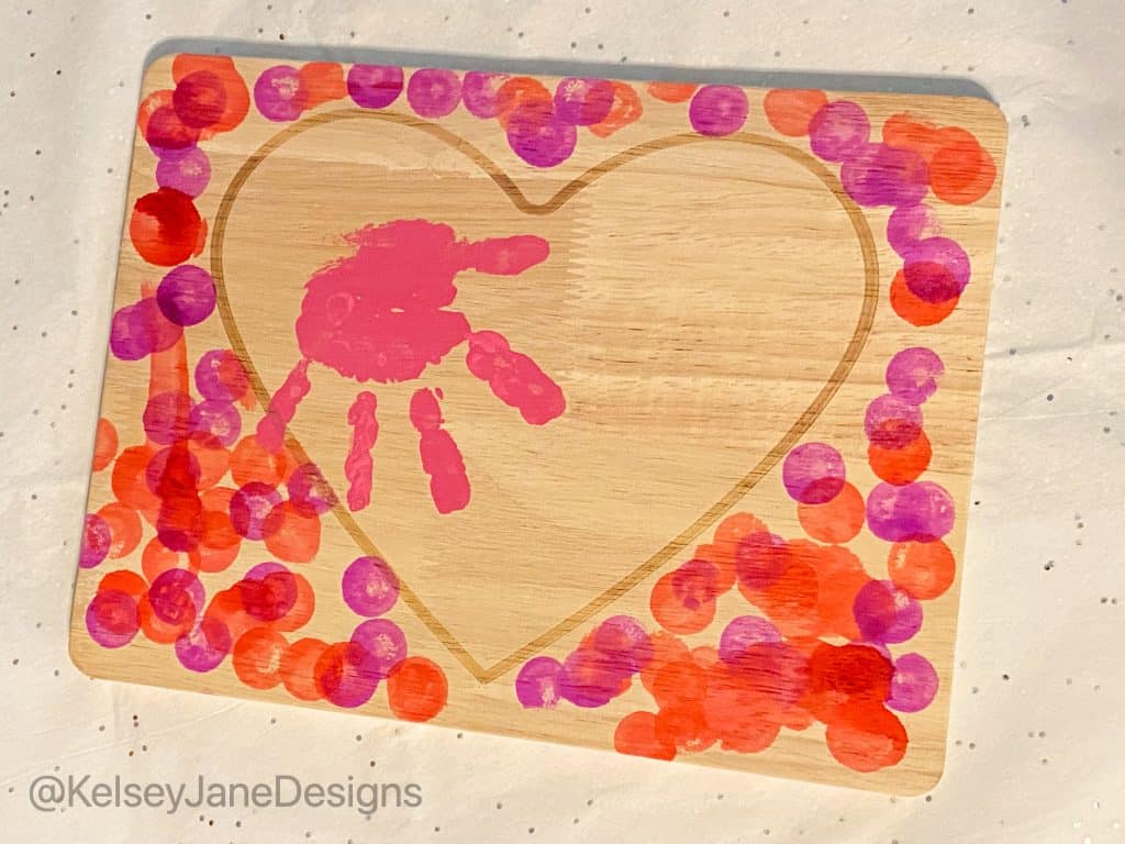 Super simple DIY handprint, or footprint, Valentine's Day home decor project that's toddler approved! Using the heart charcuterie boards from Target's Bulleyes Playground, paint, and dot markers. You'll quickly have a wonderful Valentine's Day gift for grandparents or loved ones. 