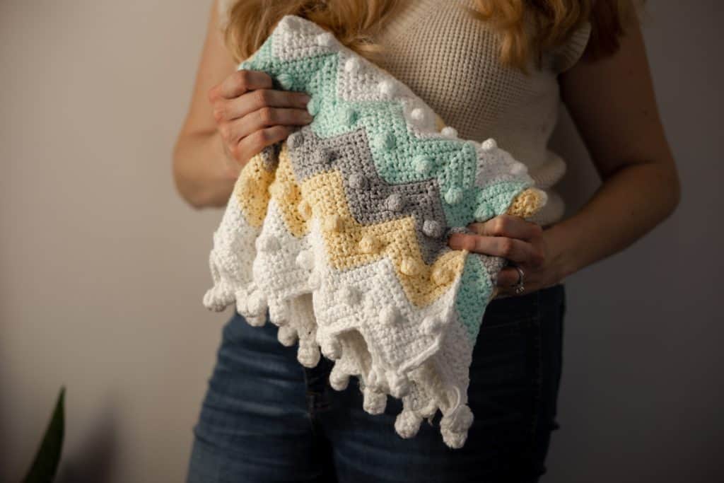 Learn how to crochet this timeless bobble chevron baby blanket with step by step instructions and YouTube video tutorial.
