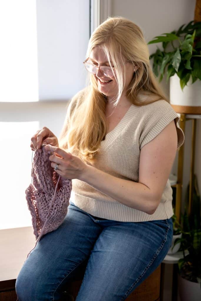 Kelsey sitting in front of window crocheting.