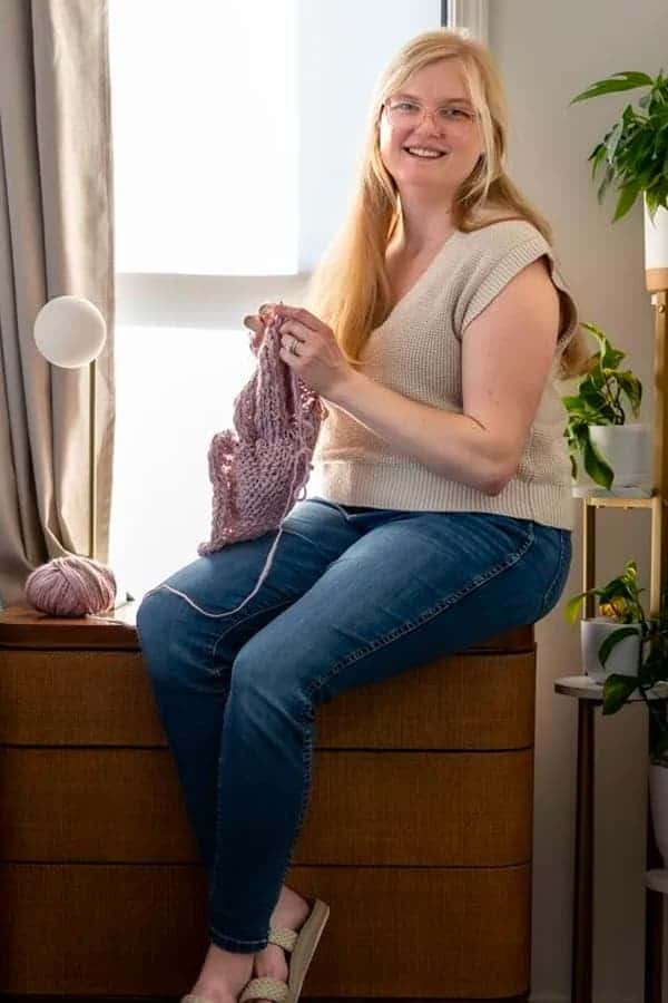 Kelsey sitting in front of window crocheting.